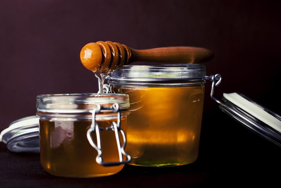 Jars of honey with a wooden dipper