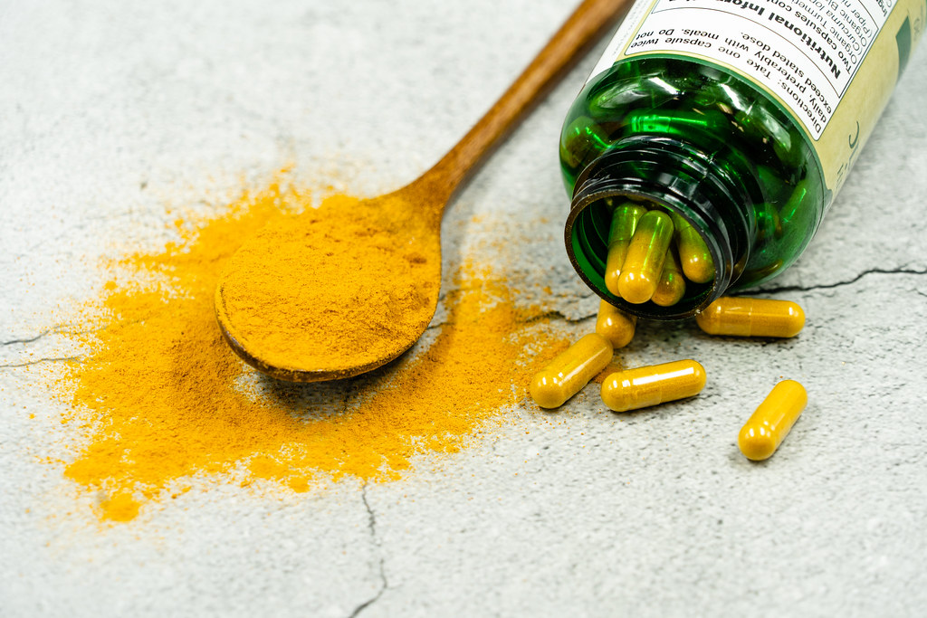 Turmeric capsules and powder on a spoon